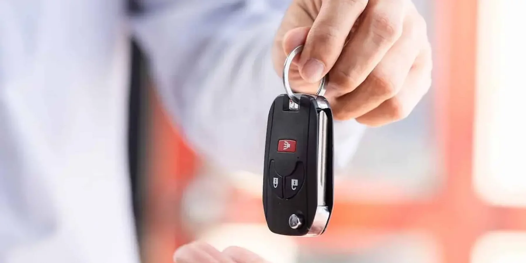 Dirk Lübcke Kraftfahrzeughandel | Ein Autoverkäufer übergibt dem Eigentümer den Autoschlüssel. Der Kunde unterzeichnet entweder ein Kaufvertrag.